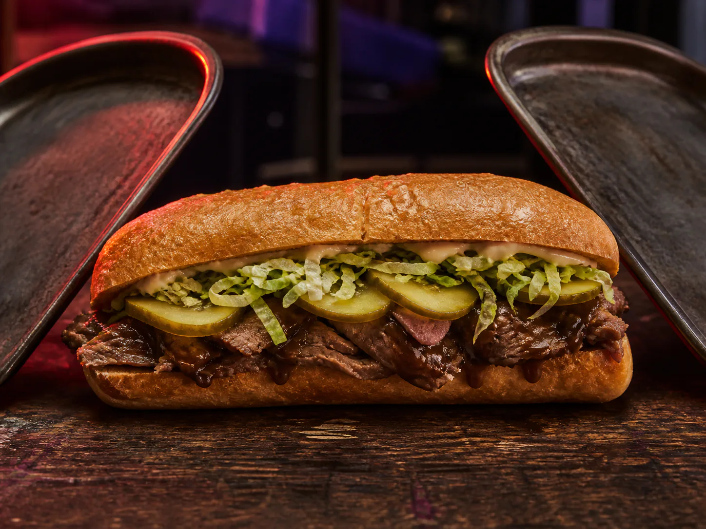 Slow-roasted beef po'boy with jus on mirrored metal plates
